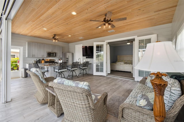 living room with wood ceiling, vaulted ceiling, ceiling fan, and light hardwood / wood-style flooring