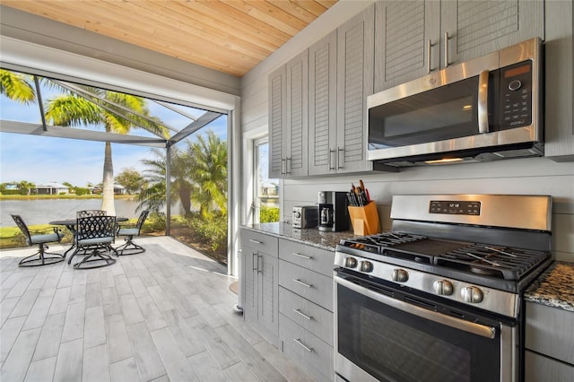 kitchen featuring gray cabinetry, wood ceiling, stainless steel appliances, light hardwood / wood-style flooring, and dark stone counters