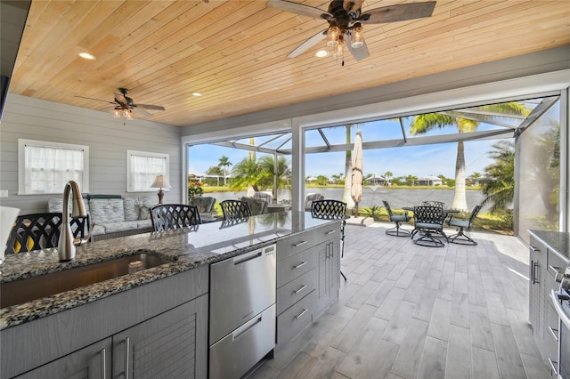 interior space with light wood-type flooring, sink, a water view, dark stone countertops, and wooden ceiling