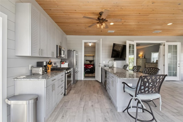 kitchen featuring a kitchen bar, white cabinetry, and stainless steel appliances