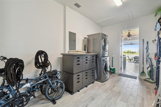 laundry area featuring light hardwood / wood-style flooring, ceiling fan, stacked washer / dryer, and electric panel