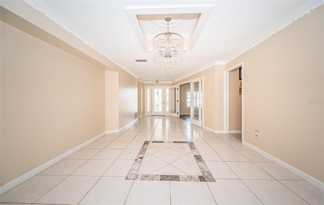 tiled empty room with ornamental molding, a tray ceiling, and a notable chandelier