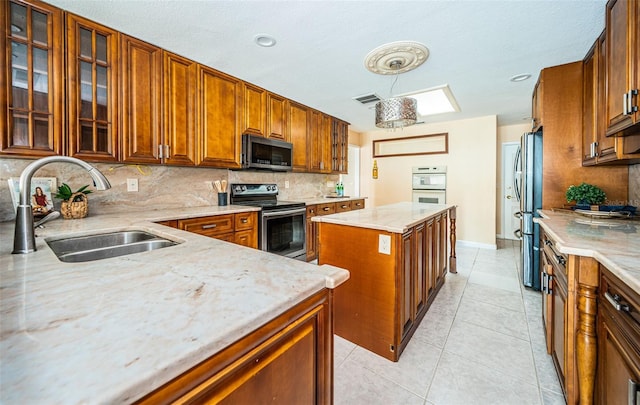 kitchen with a center island, sink, decorative backsplash, stainless steel appliances, and light stone countertops