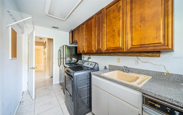 washroom with independent washer and dryer, light tile patterned floors, and sink