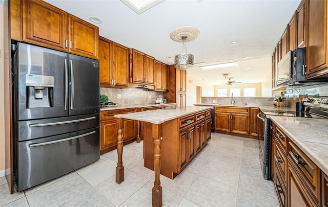 kitchen featuring ceiling fan, light tile patterned flooring, appliances with stainless steel finishes, a center island, and decorative backsplash