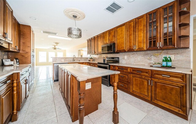 kitchen with pendant lighting, sink, a kitchen island, stainless steel appliances, and ceiling fan