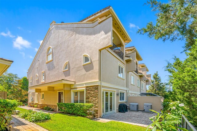 back of property with a lawn and central AC