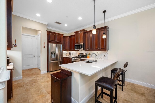 kitchen with appliances with stainless steel finishes, kitchen peninsula, pendant lighting, a kitchen bar, and sink