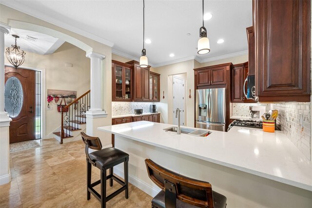 kitchen with a breakfast bar area, kitchen peninsula, decorative columns, appliances with stainless steel finishes, and decorative light fixtures