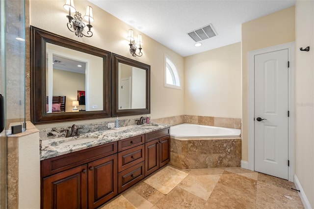 bathroom featuring a textured ceiling, tiled tub, and vanity