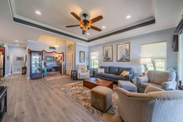 living room with light hardwood / wood-style flooring, a tray ceiling, ceiling fan, and crown molding