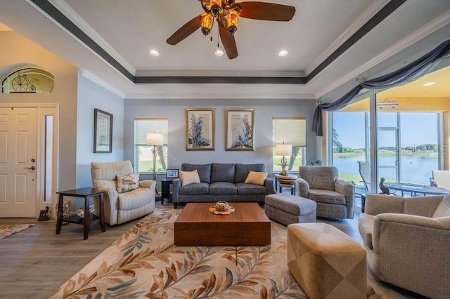 living room with hardwood / wood-style floors, plenty of natural light, ornamental molding, and a water view