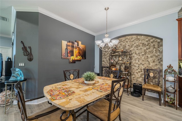 dining room with an inviting chandelier, light hardwood / wood-style flooring, and crown molding