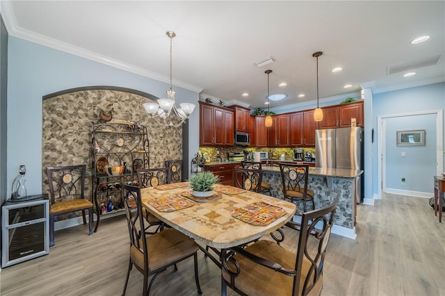 dining space featuring light wood-type flooring, a chandelier, and ornamental molding