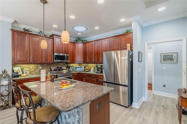 kitchen featuring pendant lighting, sink, a center island with sink, light hardwood / wood-style flooring, and stainless steel appliances