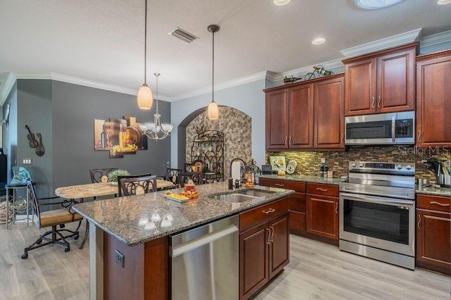 kitchen with sink, decorative light fixtures, a kitchen island with sink, stainless steel appliances, and crown molding