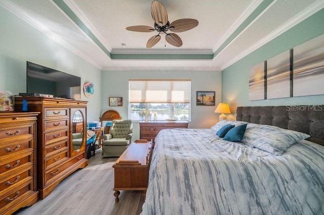 bedroom with ceiling fan, a tray ceiling, light wood-type flooring, and ornamental molding