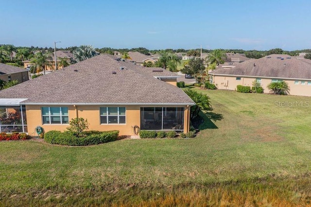 back of house featuring a lawn and a sunroom