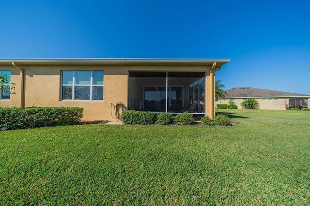 rear view of house featuring a lawn and a sunroom