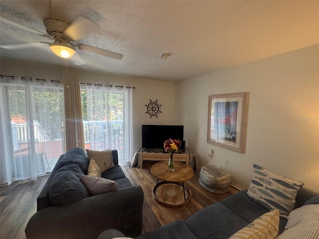 living room with a textured ceiling, ceiling fan, and wood finished floors