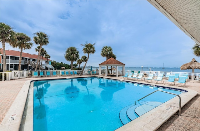 community pool with a water view, a gazebo, and fence