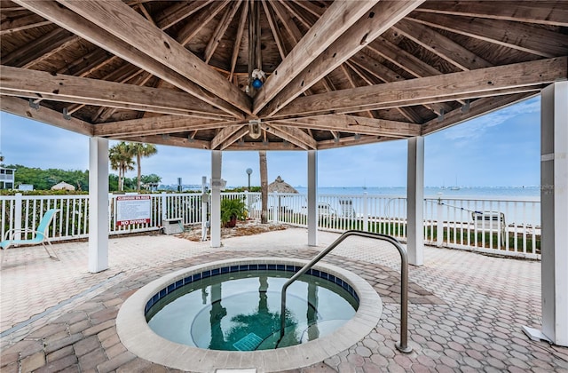 view of swimming pool with a water view, fence, a community hot tub, and a patio area