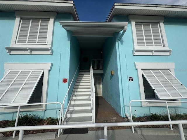 view of side of property with stucco siding and stairs