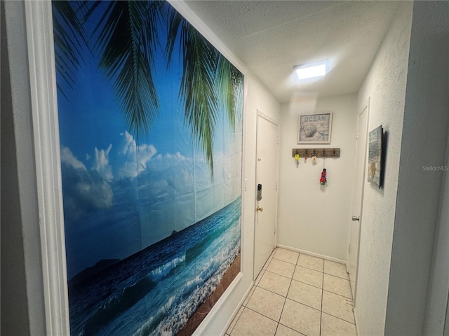 doorway to outside with a textured ceiling, light tile patterned flooring, and a textured wall