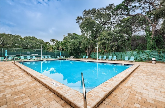 community pool with a patio area and fence