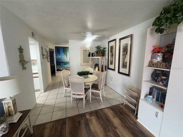 dining room featuring visible vents, a textured ceiling, wood finished floors, and a ceiling fan