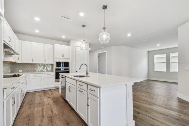 kitchen with sink, hanging light fixtures, tasteful backsplash, white cabinetry, and stainless steel appliances