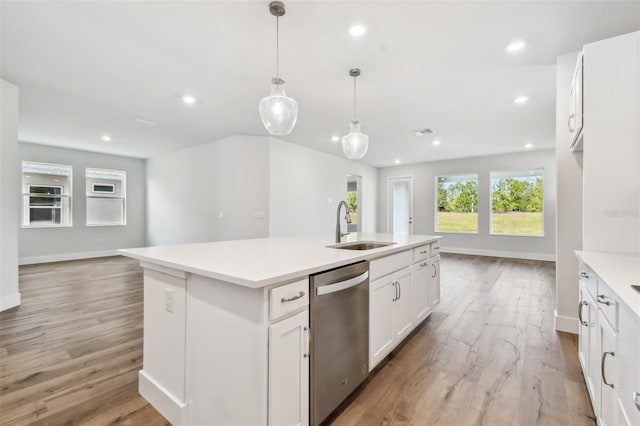 kitchen with stainless steel dishwasher, a kitchen island with sink, sink, decorative light fixtures, and white cabinetry