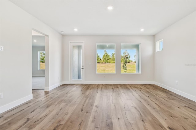 empty room with light hardwood / wood-style floors and a healthy amount of sunlight