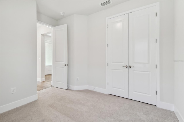 unfurnished bedroom with light colored carpet and a closet