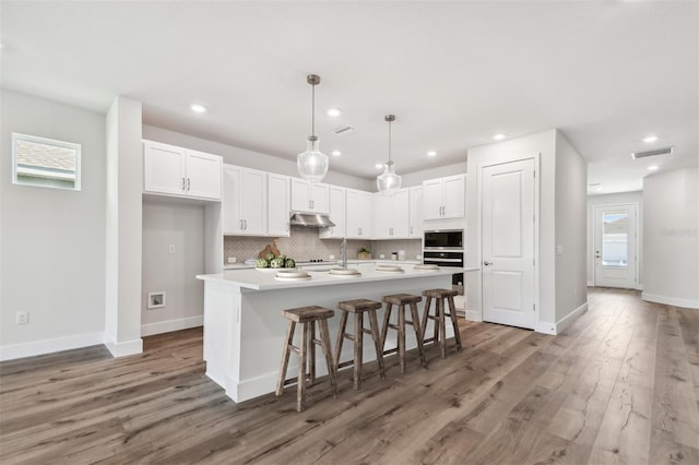 kitchen with white cabinets, backsplash, stainless steel appliances, and visible vents