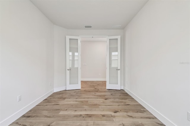 spare room featuring visible vents, baseboards, french doors, and wood finished floors