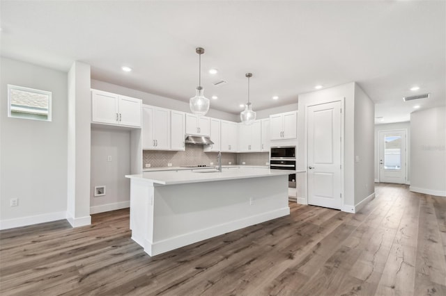 kitchen with stainless steel oven, visible vents, built in microwave, and white cabinetry