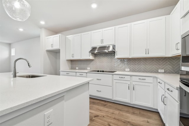 kitchen with light wood finished floors, black electric cooktop, a sink, white cabinetry, and under cabinet range hood
