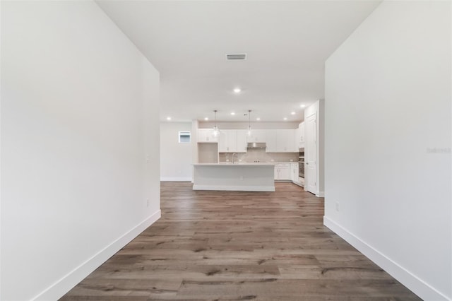 unfurnished living room featuring baseboards, light wood-style flooring, visible vents, and recessed lighting
