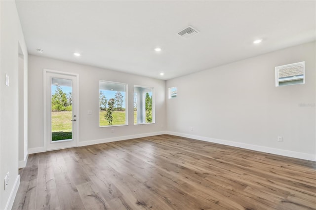 spare room with baseboards, wood finished floors, visible vents, and recessed lighting