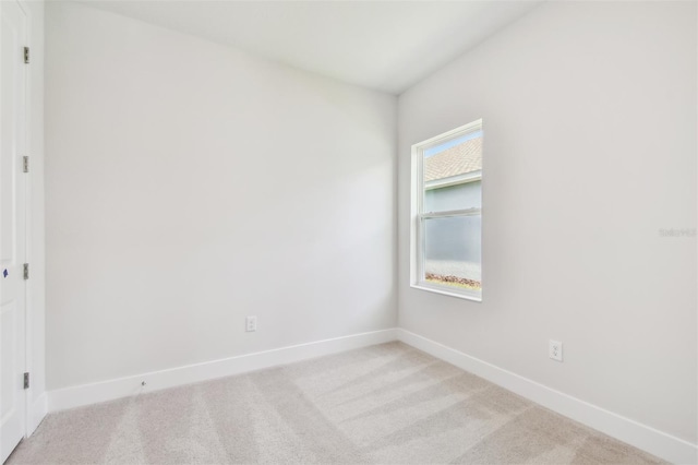spare room featuring light colored carpet and baseboards