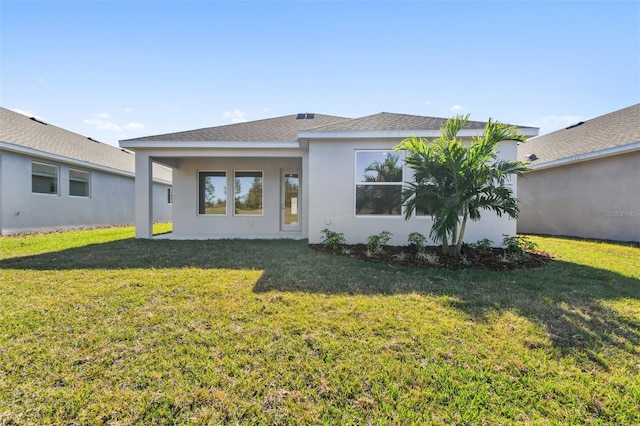 back of property with a lawn and stucco siding