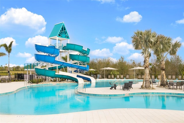 pool with a water slide, fence, and a patio