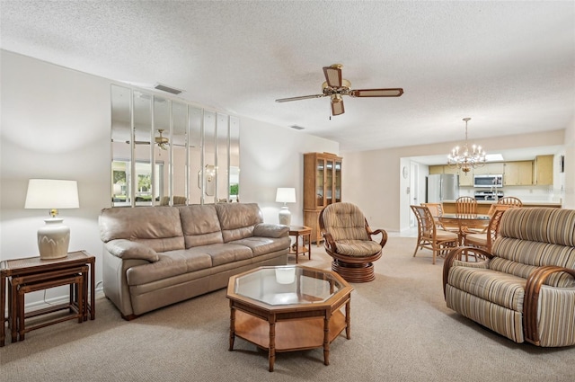 carpeted living room featuring a textured ceiling and ceiling fan with notable chandelier