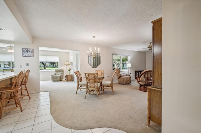 dining room with a textured ceiling, light tile patterned flooring, and ceiling fan with notable chandelier