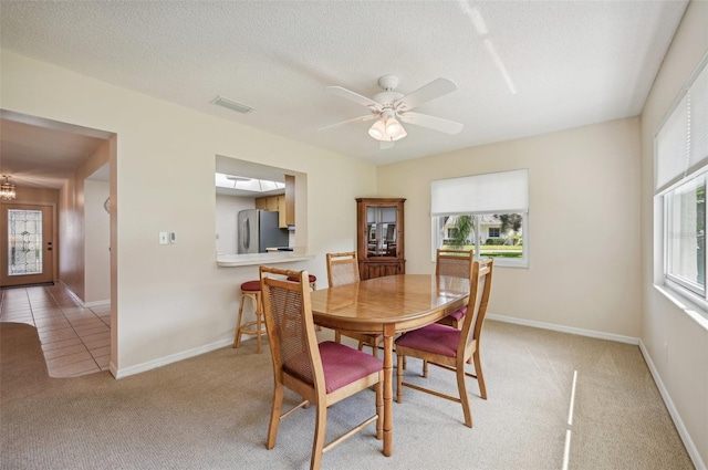 dining area featuring light carpet, a textured ceiling, a healthy amount of sunlight, and ceiling fan