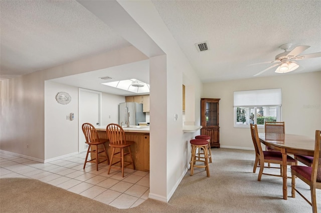 carpeted dining room featuring ceiling fan, a textured ceiling, and a skylight