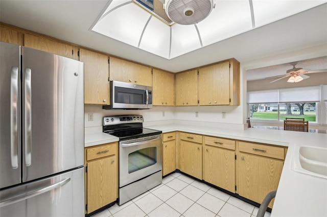 kitchen with light brown cabinets, light tile patterned flooring, stainless steel appliances, and ceiling fan