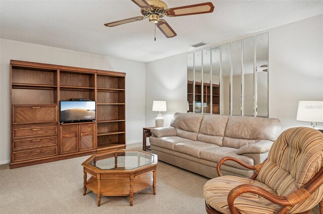 living room featuring ceiling fan, a textured ceiling, and light colored carpet