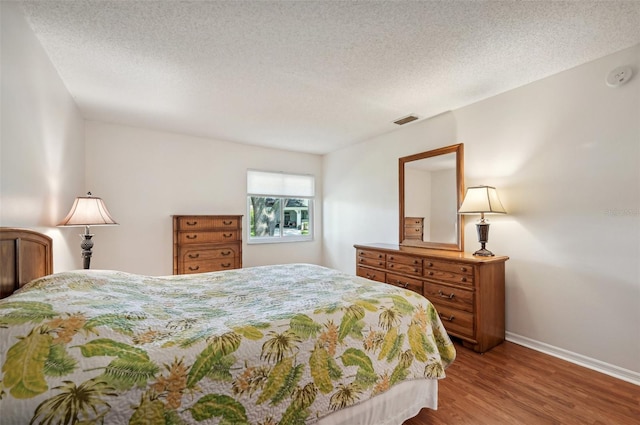 bedroom with a textured ceiling and wood-type flooring